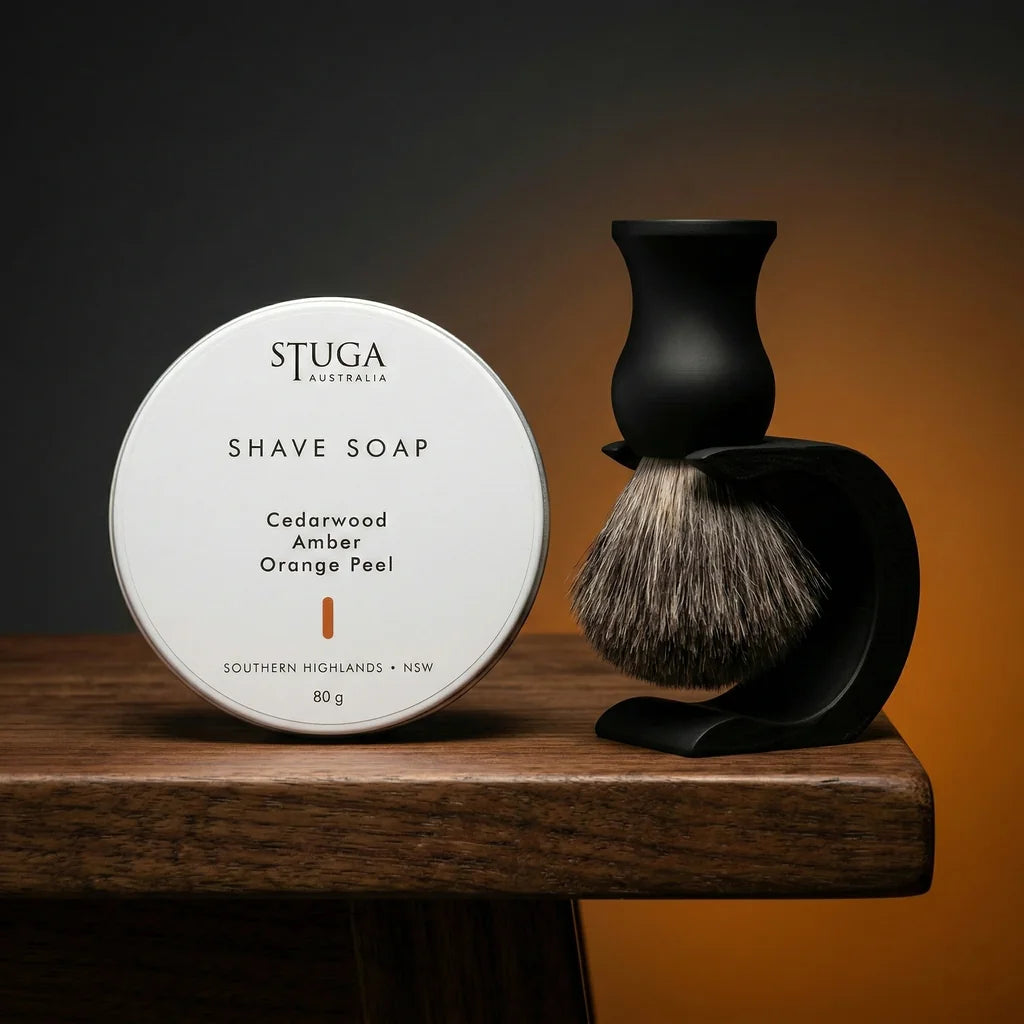 Stuga Australia cedarwood amber orange peel shave soap tin with black shaving brush on matte black stand