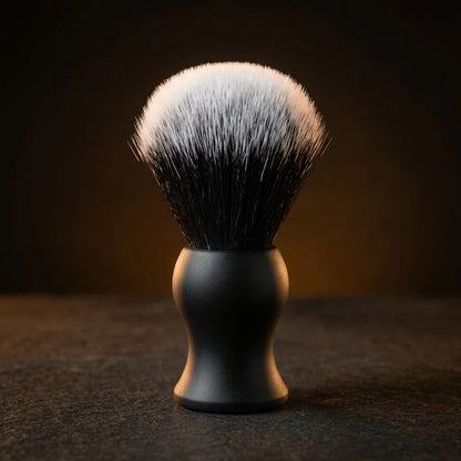 Shaving brush with matte black handle and dense synthetic bristles with white tips on dark background