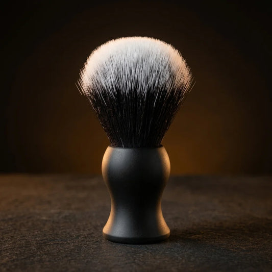 Shaving brush with matte black handle and dense synthetic bristles with white tips on dark background