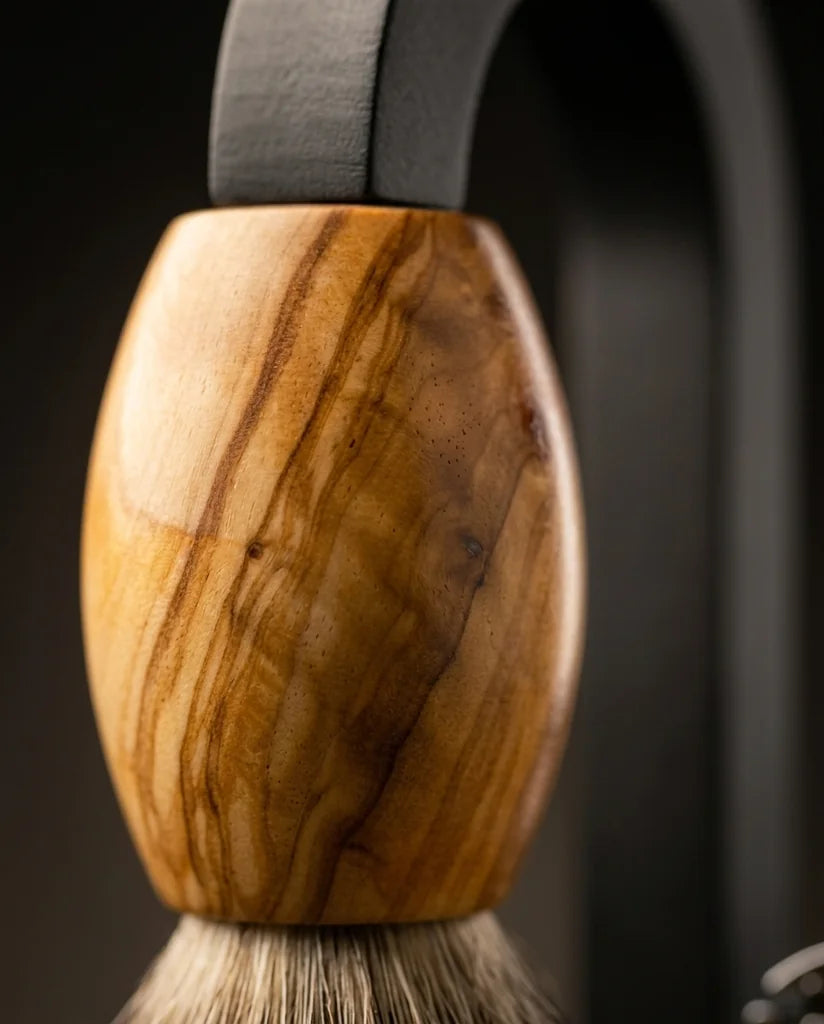 Shaving brush with polished olive wood handle and natural bristles displayed on a dark metal stand