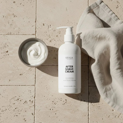 White Stuga after shave cream pump bottle with a small bowl of cream and a linen cloth on a tiled surface.