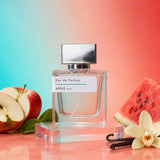 Stuga Apple No. 341 apple perfume, 50ml eau de parfum bottle with a silver cap on a clear acrylic block, with a halved red apple, a slice of watermelon, vanilla pods and a vanilla flower.