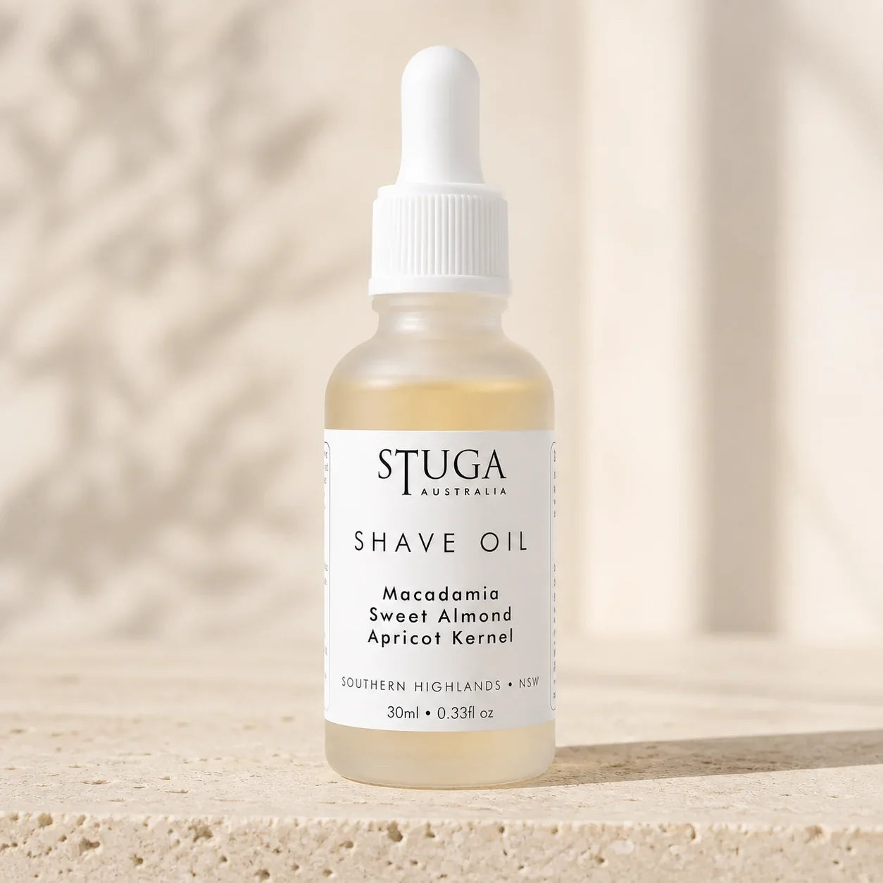 30ml Stuga Australian shave oil in a frosted glass dropper bottle on warm stone