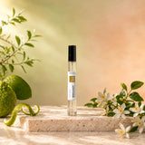 Stuga Bergamot No. 353 bergamot perfume, 10ml eau de parfum spray bottle on travertine with green bergamots, orange blossom and leafy sprigs in warm sunlight.