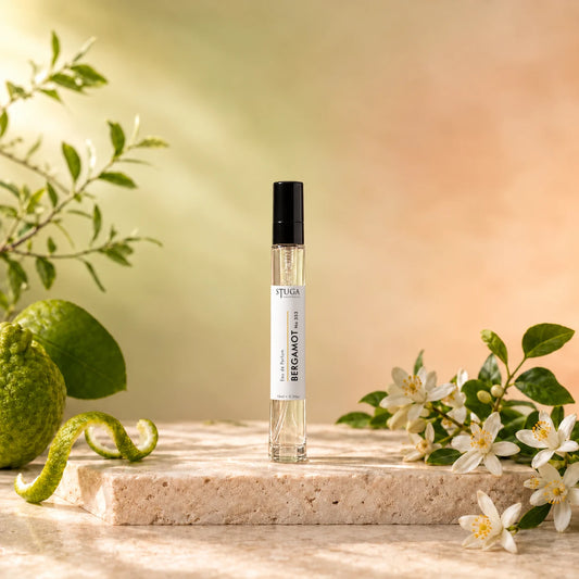 Stuga Bergamot No. 353 bergamot perfume, 10ml eau de parfum spray bottle on travertine with green bergamots, orange blossom and leafy sprigs in warm sunlight.