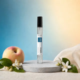 Stuga Neroli No. 437 neroli perfume, 10ml eau de parfum spray bottle on a grey stone disc, with a ripe peach, orange blossom sprigs and cream silk against a blue and gold background.