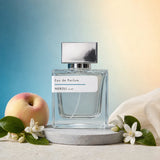 Stuga Neroli No. 437 neroli perfume, 50ml eau de parfum bottle with a silver cap on a grey stone disc, with a ripe peach, orange blossom sprigs and cream silk against a blue and gold background.