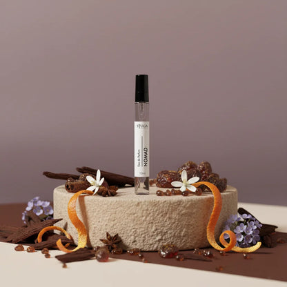 Stuga Nomad 10ml Eau de Parfum spray bottle on a stone pedestal, surrounded by cinnamon sticks, star anise, orange peel, and 