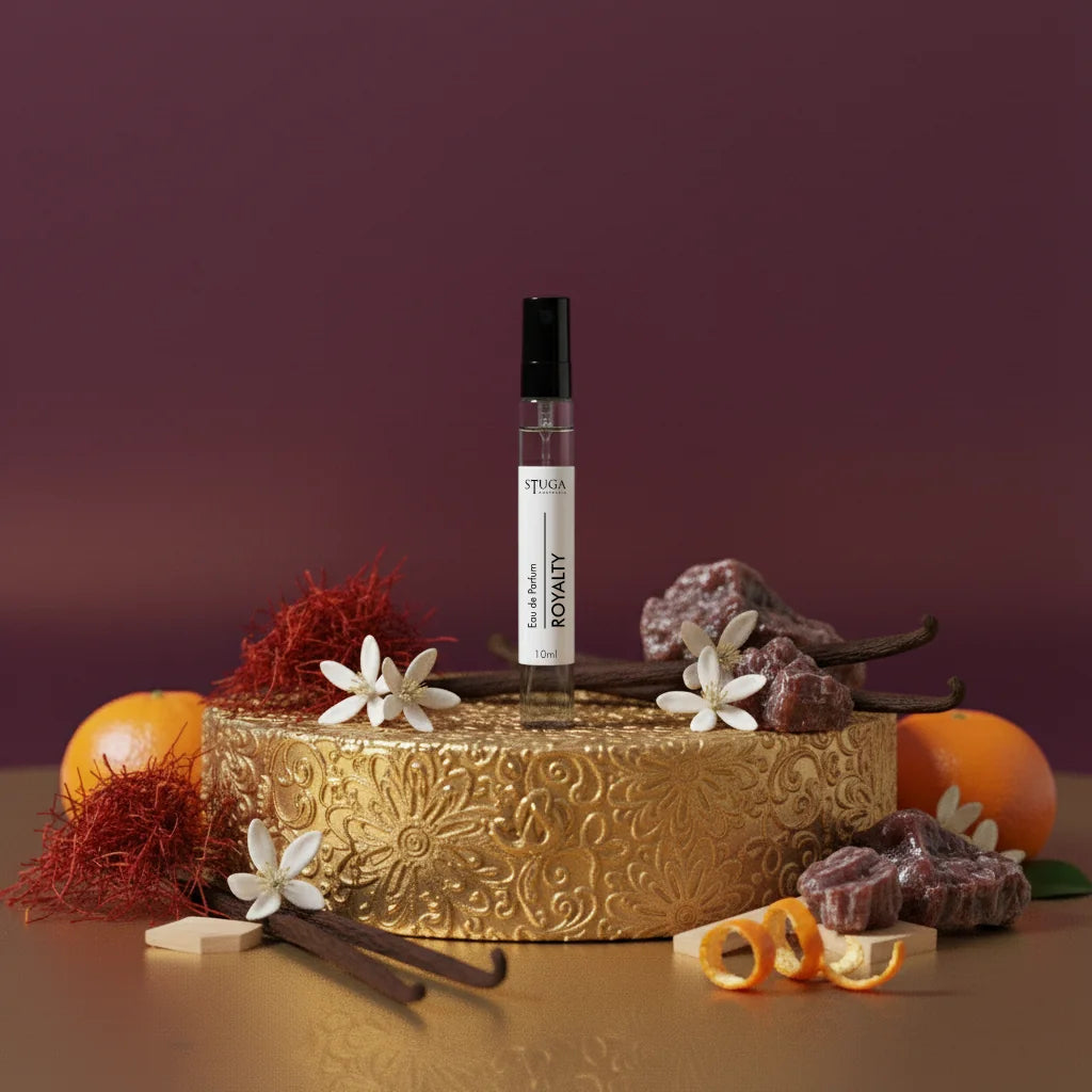 Stuga Royalty EDP 10ml perfume bottle on a gold stand, surrounded by saffron, vanilla pods, orange peels, and white flowers.