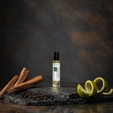 Stuga Sandalwood No. 413 sandalwood oil perfume, 10ml roll-on bottle on slate with sandalwood sticks, black peppercorns and a lime peel twist.