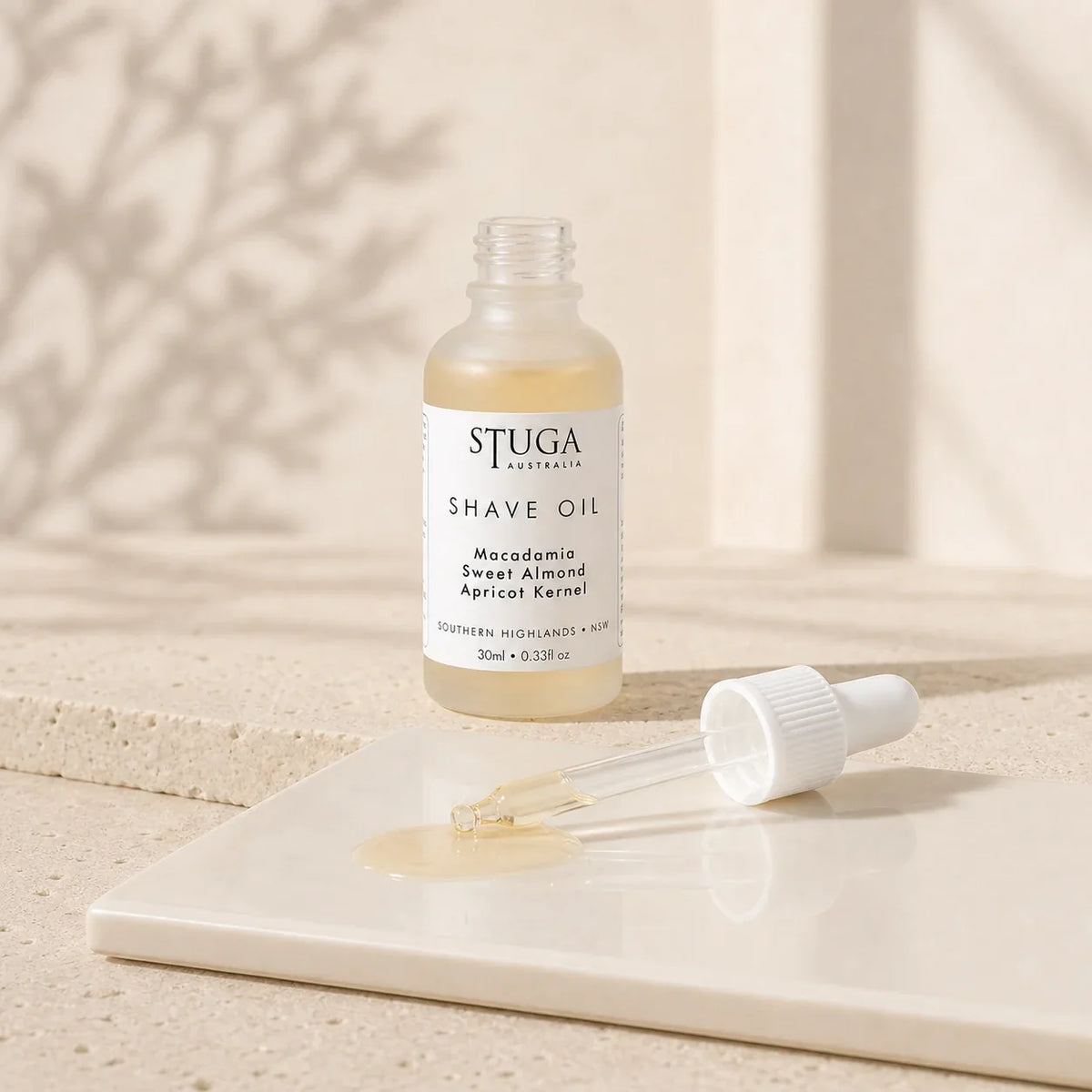 Open 30ml Stuga shave oil bottle with dropper and pale golden oil on a glossy tile