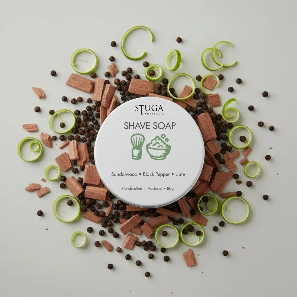 Stuga Australia shave soap tin, sandalwood, black pepper, lime, surrounded by wood chips, peppercorns, and lime zest.