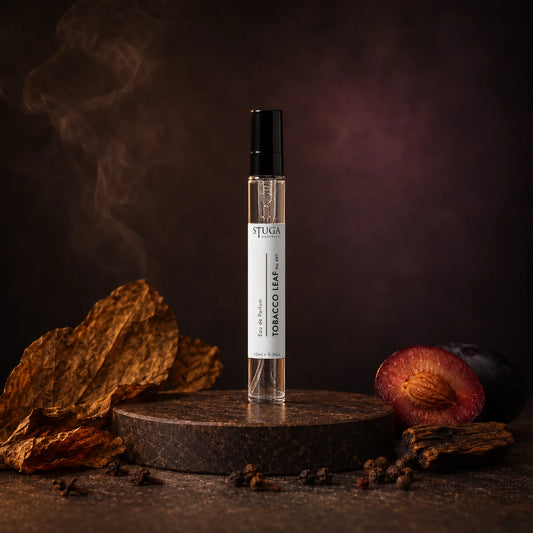 Stuga Tobacco Leaf No. 407 tobacco perfume, 10ml eau de parfum spray bottle on a dark stone plinth with dried tobacco leaves, a spiced plum and drifting smoke.