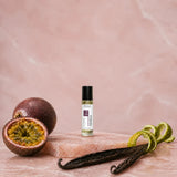 Stuga Vanilla No. 313 vanilla oil perfume, 10ml roll-on bottle on pink marble with halved passionfruit, orange zest and vanilla beans.