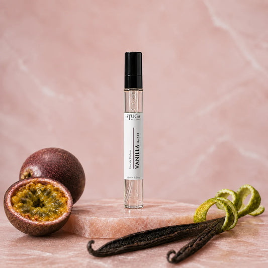 Stuga Vanilla No. 313 vanilla perfume, 10ml eau de parfum spray bottle on pink marble with halved passionfruit, orange zest and vanilla beans.