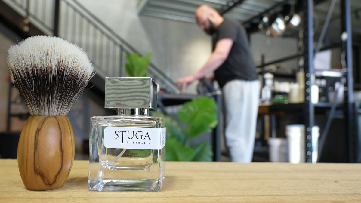 Stuga shaving brush and perfume bottle on the workshop bench, Nicklas working in the background
