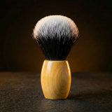 Synthetic shaving brush with dense black-to-white tipped bristles and a polished olive wood handle