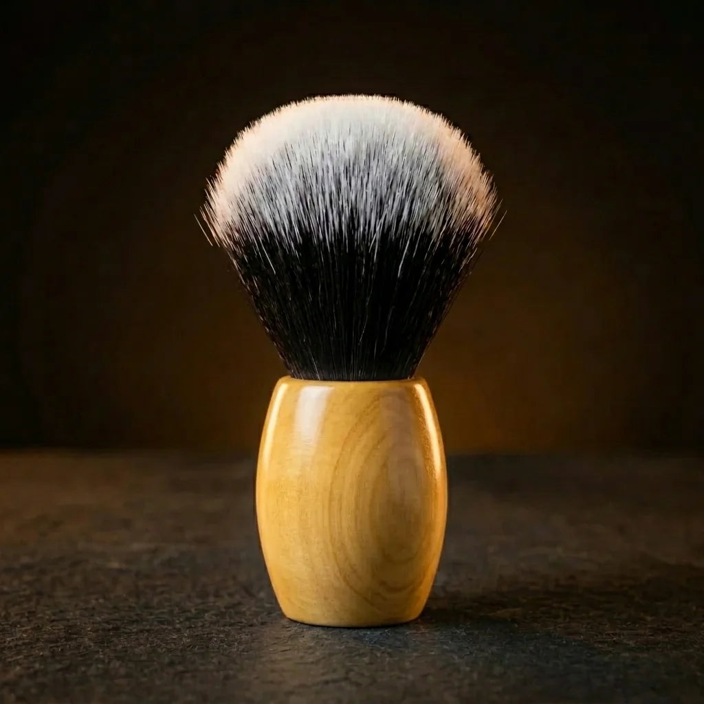 Synthetic shaving brush with dense black-to-white tipped bristles and a polished olive wood handle