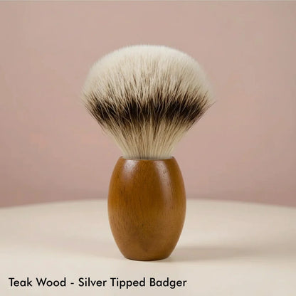 Teak wood handle shaving brush with silver tipped badger bristles on a light background.