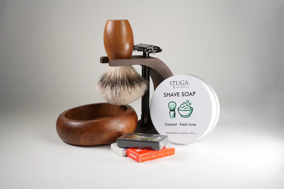 Wooden shaving brush and bowl set with metal razor, coconut fresh lime shave soap, and razor blades on white background