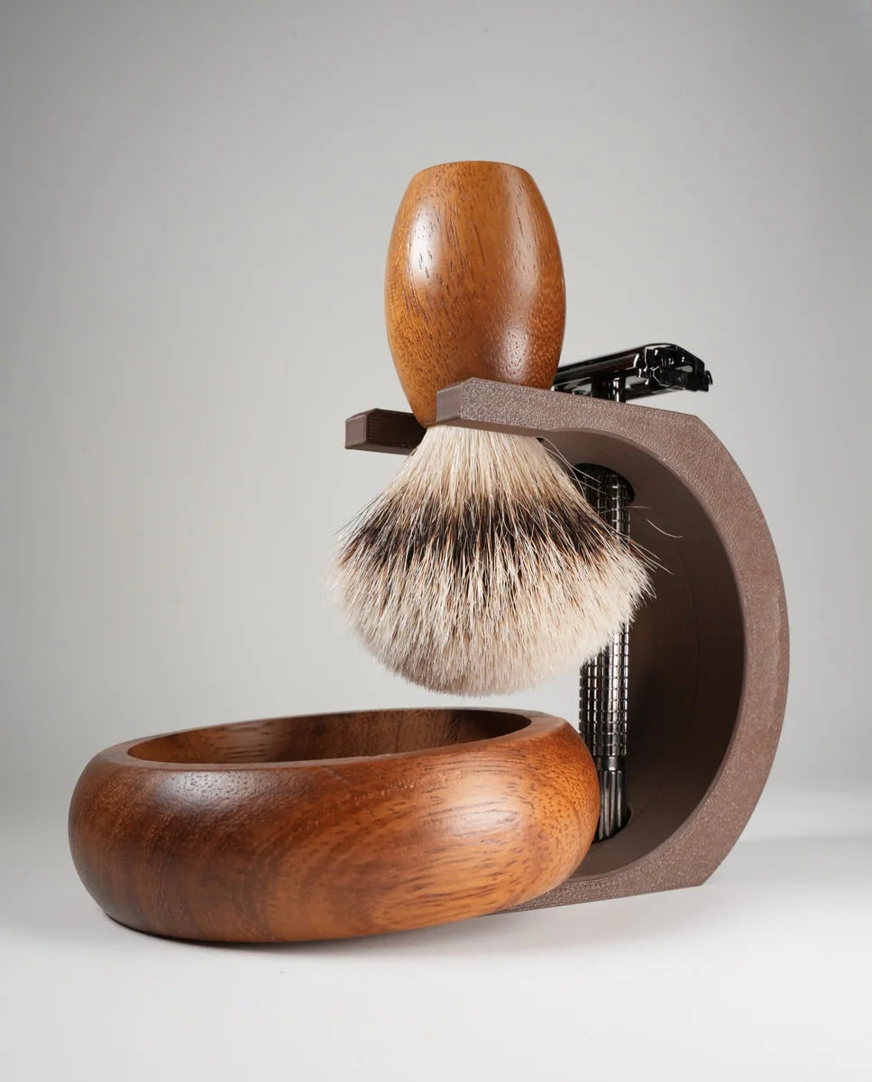 Wooden shaving brush with natural bristles on a brown stand next to a matching wooden shaving bowl